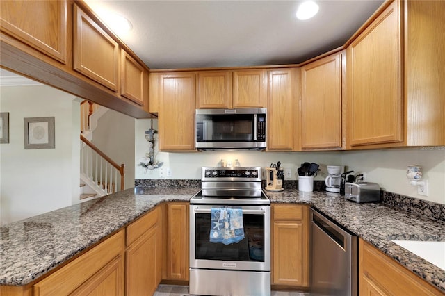 kitchen featuring stainless steel appliances, dark stone counters, a peninsula, and recessed lighting