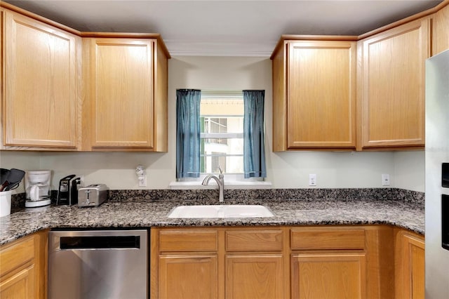 kitchen with crown molding, stainless steel appliances, light brown cabinetry, a sink, and dark stone countertops