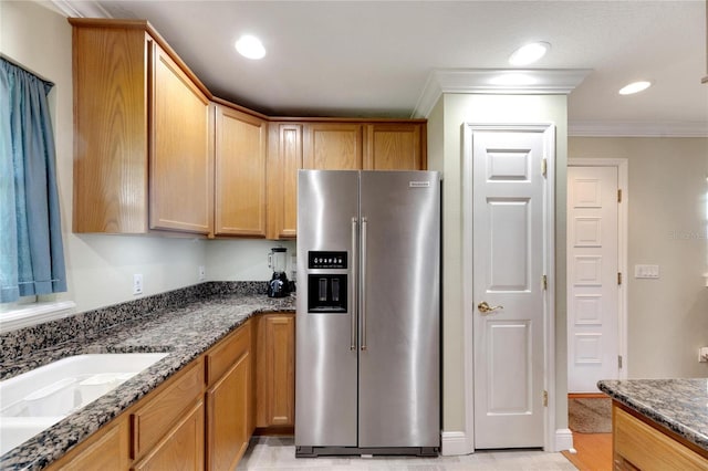 kitchen with recessed lighting, ornamental molding, high quality fridge, a sink, and dark stone counters