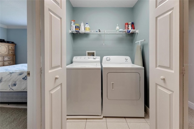 washroom featuring washing machine and clothes dryer, ornamental molding, and light tile patterned floors