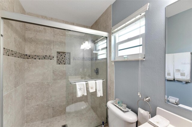 full bathroom featuring a textured wall, a shower stall, and toilet