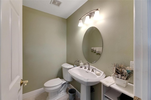 half bath with baseboards, visible vents, and toilet