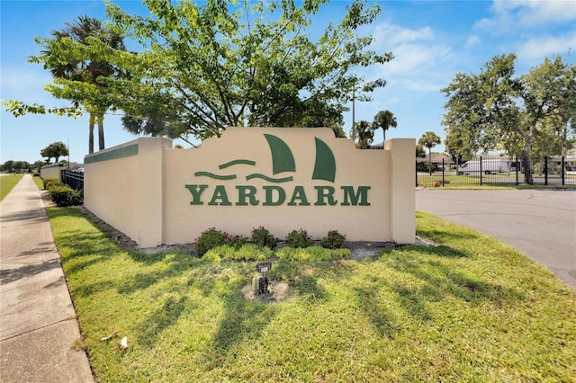 community / neighborhood sign with a lawn and fence