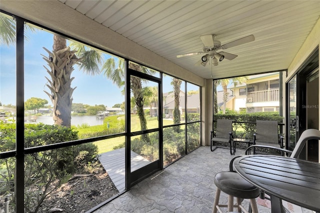 sunroom featuring ceiling fan and a water view