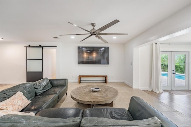 living room with a barn door, ceiling fan, and french doors