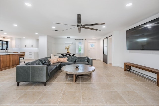 tiled living room with a barn door, sink, and ceiling fan