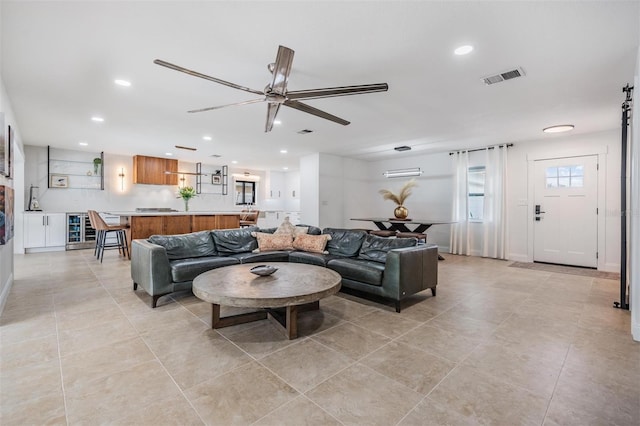 living room with ceiling fan, beverage cooler, and light tile patterned floors