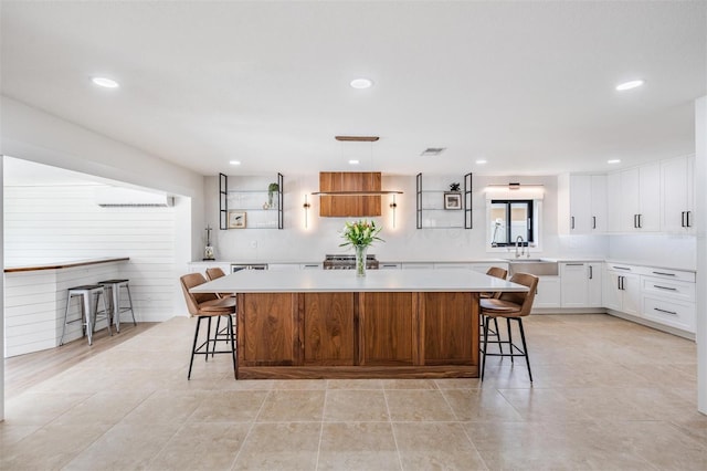 kitchen featuring a breakfast bar, sink, white cabinets, and a spacious island