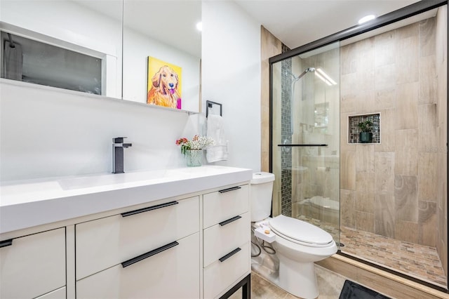 bathroom with vanity, toilet, and a shower with shower door