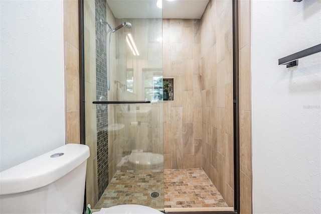 bathroom featuring a shower with shower door and toilet