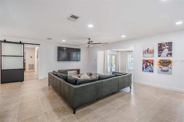 tiled living room with a barn door and ceiling fan