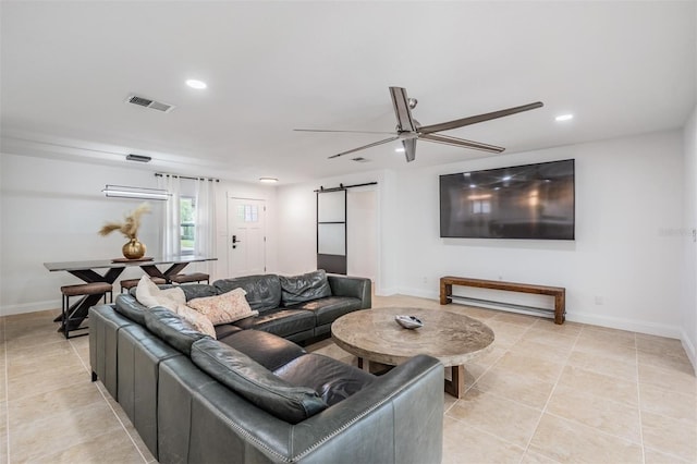 living room featuring light tile patterned flooring, a barn door, and ceiling fan