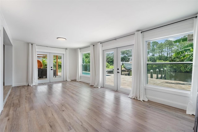 spare room featuring french doors, a water view, and light wood-type flooring