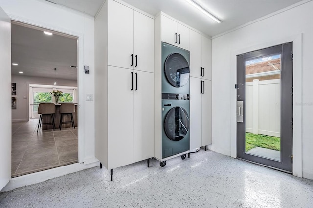 laundry room featuring cabinets and stacked washer and clothes dryer