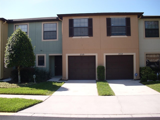 townhome / multi-family property featuring driveway, an attached garage, and stucco siding