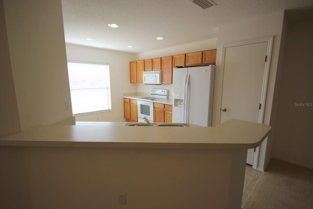 kitchen with white appliances, kitchen peninsula, and a textured ceiling