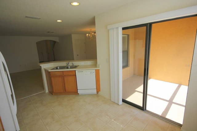 kitchen with white appliances, brown cabinets, decorative light fixtures, light countertops, and a sink