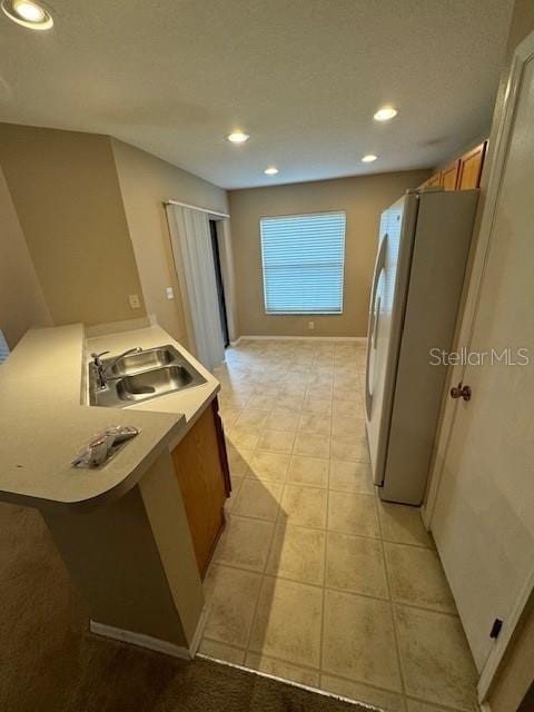 kitchen with a textured ceiling, white fridge, and sink