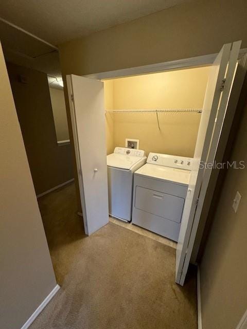 clothes washing area with washer and clothes dryer and light carpet