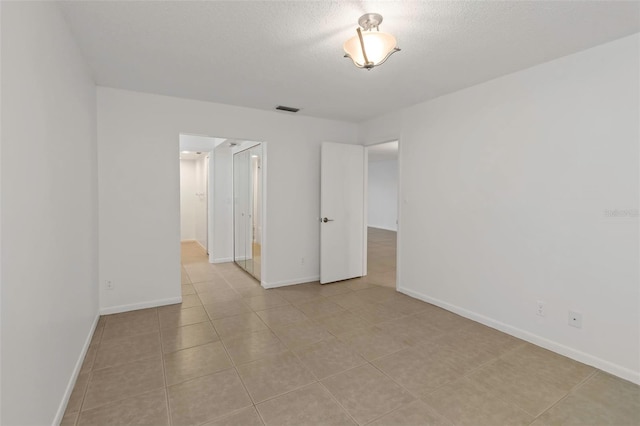 tiled spare room with a textured ceiling