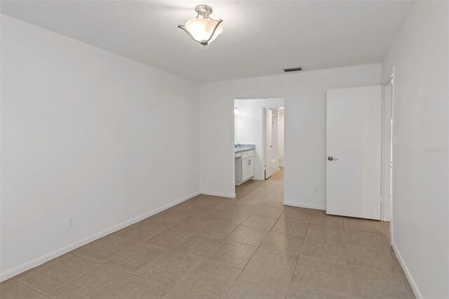 tiled spare room featuring a textured ceiling