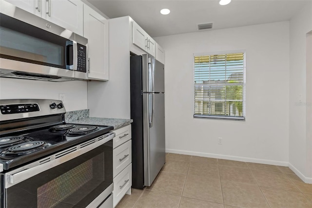 kitchen with light tile patterned flooring, appliances with stainless steel finishes, light stone countertops, and white cabinets