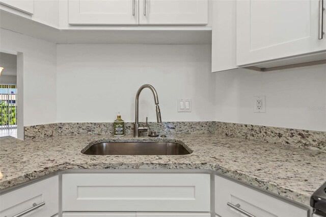 kitchen featuring sink, white cabinets, and light stone counters