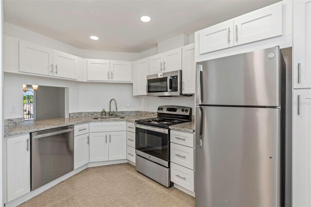 kitchen featuring white cabinetry, stainless steel appliances, light stone counters, and light tile patterned floors