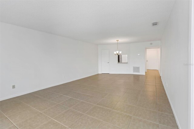 unfurnished living room with a notable chandelier and light tile patterned floors