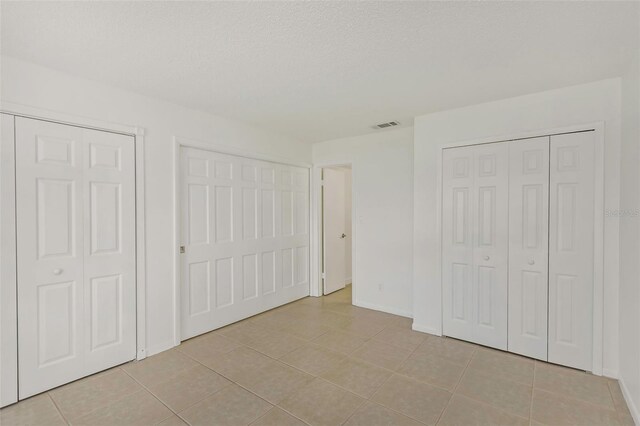 unfurnished bedroom featuring multiple closets and light tile patterned floors