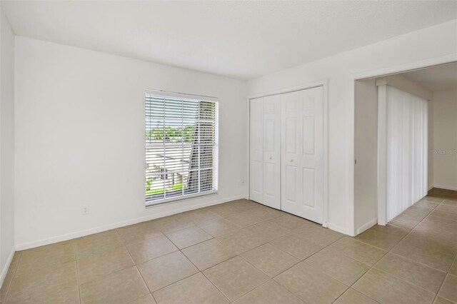 unfurnished bedroom with a closet and light tile patterned floors