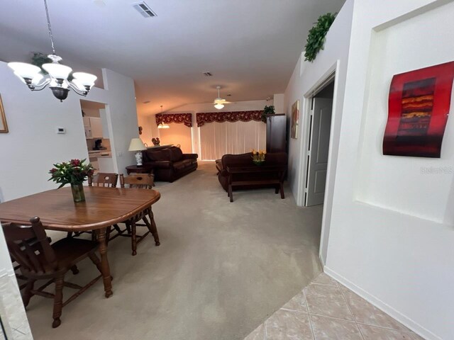 tiled dining space featuring ceiling fan with notable chandelier