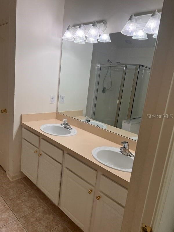 bathroom with double vanity, walk in shower, and tile patterned flooring