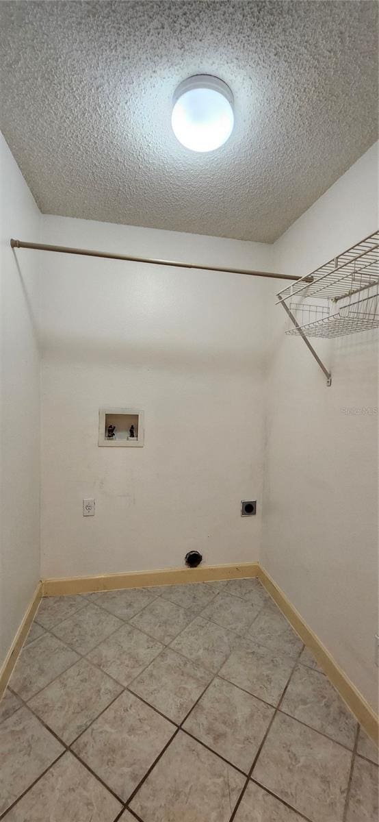 clothes washing area with hookup for an electric dryer, tile patterned flooring, a textured ceiling, and hookup for a washing machine