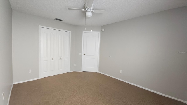 unfurnished bedroom with a textured ceiling, a closet, dark carpet, and ceiling fan