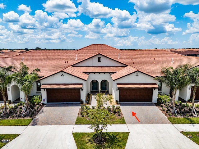 mediterranean / spanish home featuring decorative driveway, an attached garage, and a tile roof