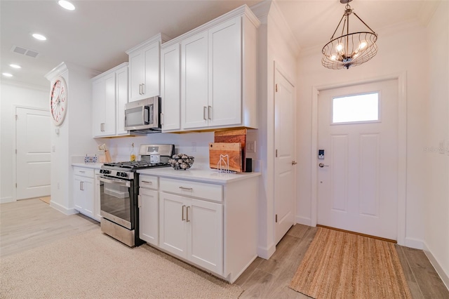 kitchen featuring light hardwood / wood-style flooring, stainless steel appliances, white cabinets, pendant lighting, and ornamental molding