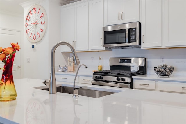 kitchen with white cabinetry, appliances with stainless steel finishes, sink, and ornamental molding