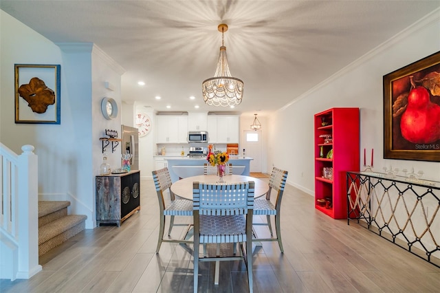 dining space with an inviting chandelier, crown molding, and light wood-type flooring