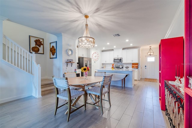 dining room featuring ornamental molding, light wood-type flooring, and a chandelier