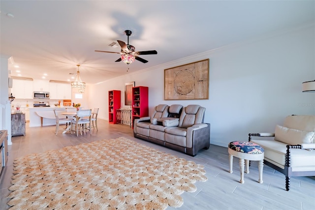 living room featuring ceiling fan with notable chandelier and crown molding