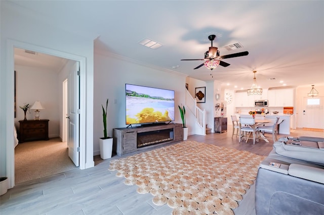 carpeted living room with ceiling fan with notable chandelier