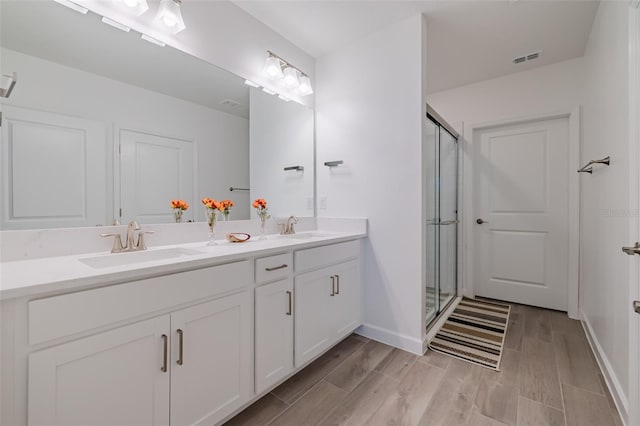 bathroom featuring dual vanity, a shower with shower door, and hardwood / wood-style flooring