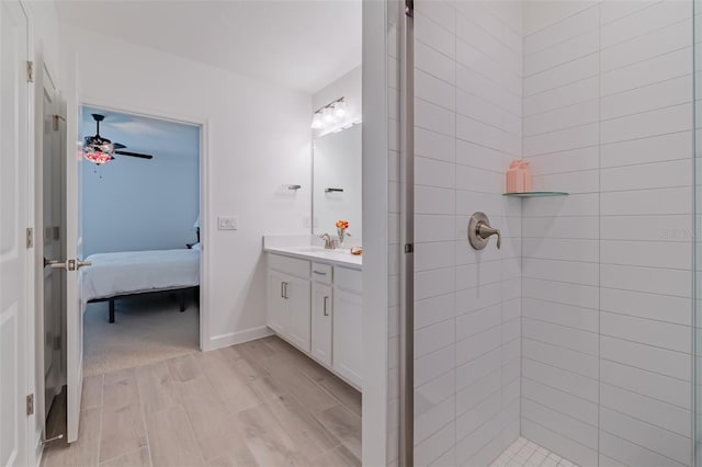 bathroom featuring a tile shower, vanity, ceiling fan, and wood-type flooring