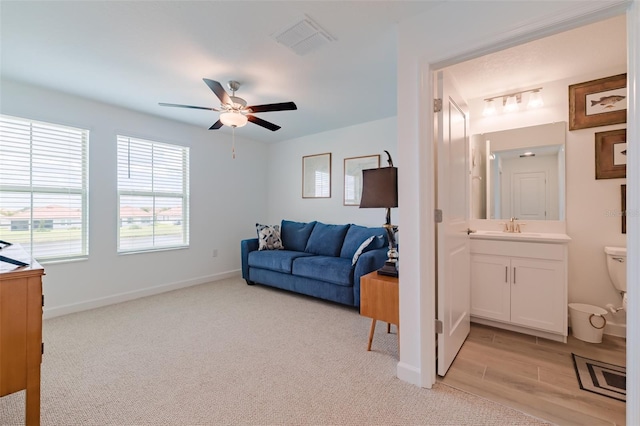 living room featuring light carpet, sink, and ceiling fan