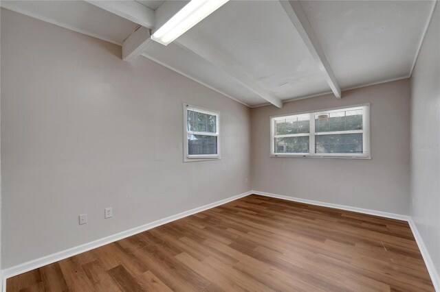 empty room featuring lofted ceiling with beams and hardwood / wood-style flooring