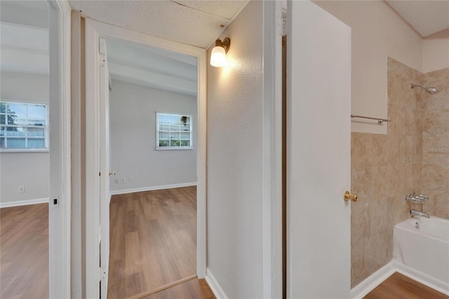 bathroom featuring hardwood / wood-style flooring, a textured ceiling, and tub / shower combination