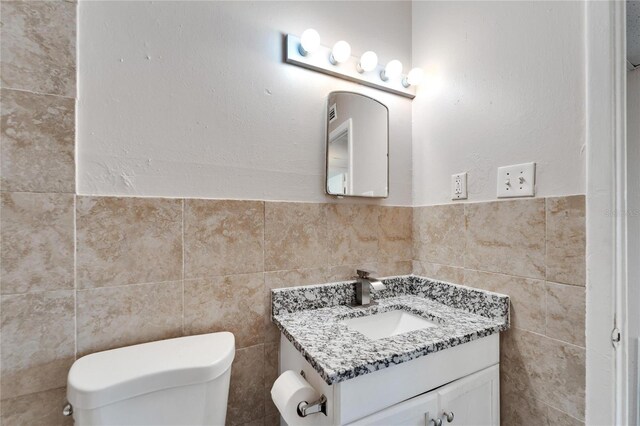 bathroom with vanity, tile walls, and toilet