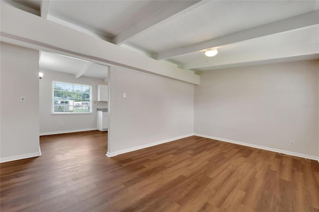 spare room featuring beamed ceiling and hardwood / wood-style floors