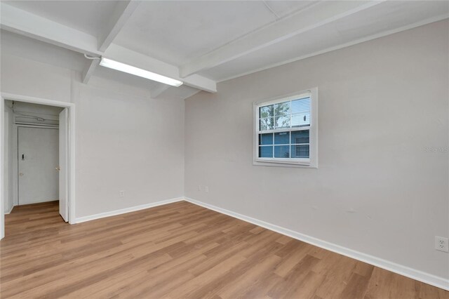 unfurnished room with beamed ceiling and wood-type flooring